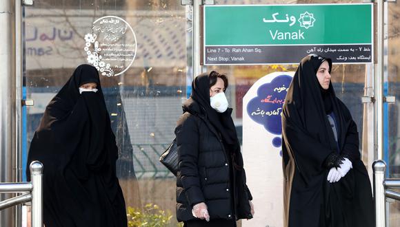 Un grupo de mujeres que lleva máscaras protectoras contra el coronavirus espera el bus en una estación de Teherán, la capital de Irán. (AFP / ATTA KENARE).