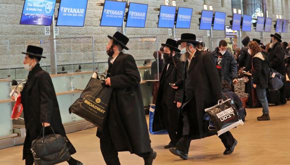Los viajeros judíos ultraortodoxos caminan con su equipaje antes de sus vuelos de salida en el aeropuerto Ben Gurion de Israel, el 21 de diciembre de 2021, en plena pandemia de coronavirus. (GIL COHEN-MAGEN / AFP).