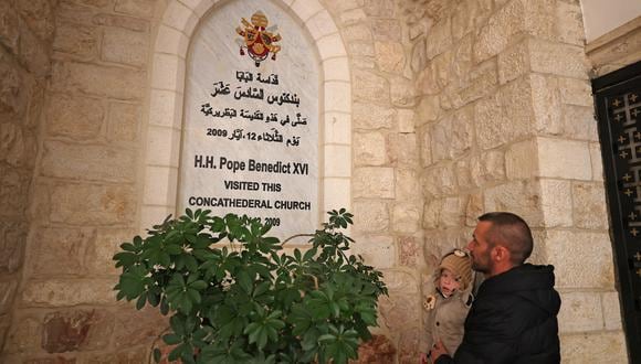 Un hombre mira una placa en honor a la visita del difunto Papa Emérito Benedicto XVI a la Concatedral de los Latinos en Jerusalén el 1 de enero de 2023. (Foto de AHMAD GHARABLI / AFP)