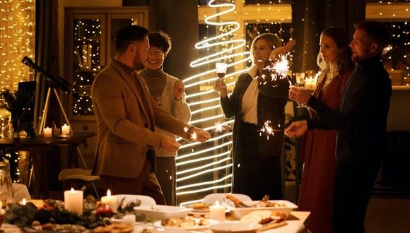 Familia celebrando la Navidad sosteniendo bengalas encendidas. (Imagen: Nicole Michalou / Pexels)