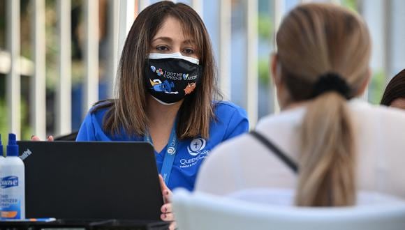 Una trabajadora de salud habla con una mujer que llega para recibir su primera vacuna Pfizer Covid-19 en un evento de atención médica comunitaria en un vecindario predominantemente latino en Los Ángeles, California, el 11 de agosto de 2021.  (Foto de Robyn Beck / AFP)