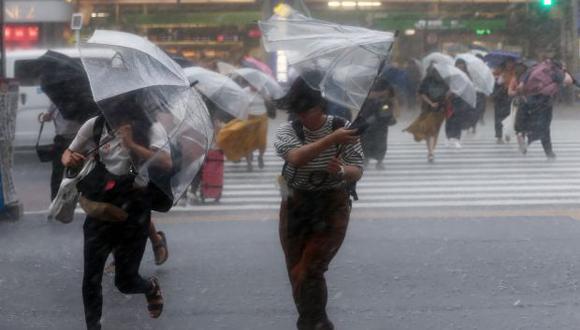 Las personas se protegen con sombrillas cuando caen las fuertes lluvias causadas por el tifón en Tokio. (Foto referencial: AFP)