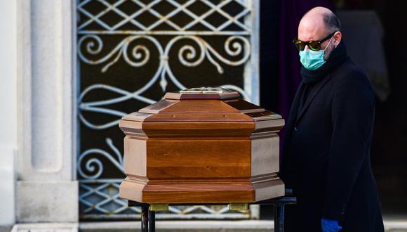 Un hombre con una máscara facial mira el ataúd de su madre durante un funeral en el cementerio cerrado de Seriate, cerca de Bérgamo, Lombardía, la región de Italia más golpeada por el coronavirus. (AFP / Piero Cruciatti).