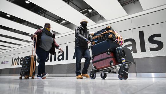 Los pasajeros con máscaras faciales como medida de precaución contra el COVID-19 caminan por la sala de llegadas después de aterrizar en el aeropuerto de Heathrow, en el oeste de Londres (Reino Unido), el 15 de enero de 2021. (DANIEL LEAL-OLIVAS / AFP).