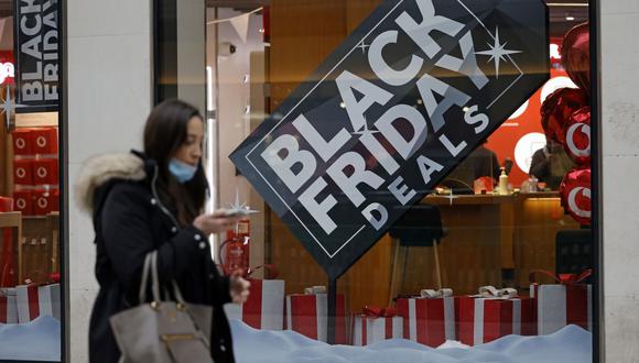 Una mujer que usa mascarilla protectora contra la propagación del coronavirus, pasa junto a un letrero de "Black Friday Deals" en el escaparate de una tienda en el centro de Londres, Inglaterra. (Foto de Tolga Akmen / AFP).