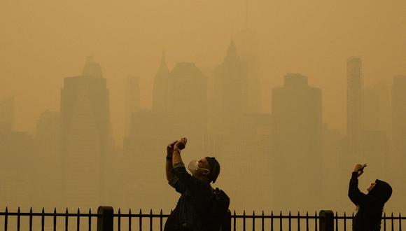Gente toma fotos del sol mientras el humo de los incendios forestales en Canadá provoca condiciones de niebla en la ciudad de Nueva York el 7 de junio de 2023. (Foto de ANGELA WEISS / AFP)