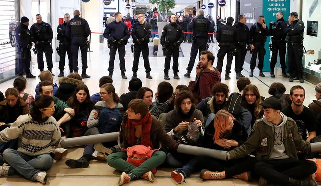 Los activistas se sientan frente a la policía francesa mientras bloquean un pasillo del centro comercial Westfield Les 4 Temps, cerca de París. (Foto: Reuters)