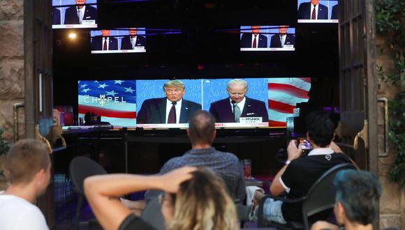 La gente se sienta y mira una transmisión del primer debate entre Donald Trump y  Joe Biden en West Hollywood, California. Foto del 29 de setiembre de 2020. (Mario Tama/Getty Images/AFP).