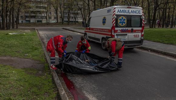 Médicos colocan el cuerpo de un civil muerto en una bolsa para cadáveres en la zona residencial que fue alcanzada por el bombardeo de artillería rusa en Kharkiv, noreste de Ucrania, el 19 de abril de 2022. (EFE/EPA/ROMAN PILIPEY).