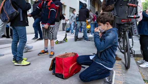 Un niño se ajusta la máscara protectora antes de ingresar a su escuela primaria, en París, el 26 de abril de 2021, cuando las escuelas primarias y los jardines de infancia franceses reabren después de tres semanas de cierre. (Foto: Thomas SAMSON / AFP)