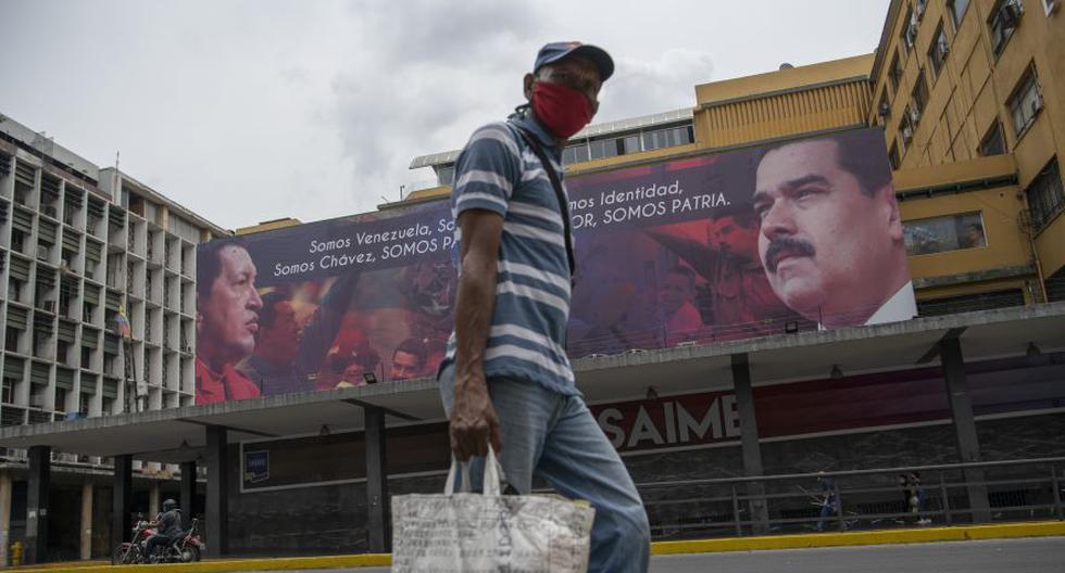 Un peatón con una máscara protectora pasa por una valla publicitaria con una imagen de Nicolás Maduro en Caracas. (Foto: Carlos Becerra/Bloomberg).