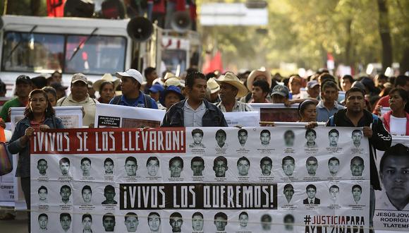Personas sostienen carteles con imágenes de los 43 estudiantes desaparecidos de Ayotzinapa, durante una manifestación exigiendo información sobre su paradero en la Ciudad de México el 5 de noviembre de 2014. (Foto de RONALDO SCHEMIDT / AFP)