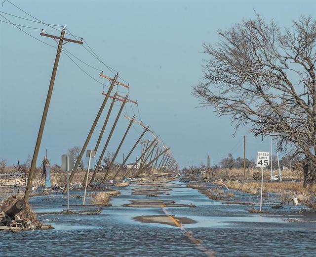 Postes de servicios públicos inclinados a lo largo de una carretera inundada en Cameron, Louisiana, tras el impacto del huracán Delta. (EFE / EPA / TANNEN MAURY).