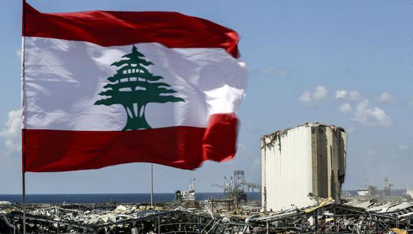 Una bandera de Líbano flamea cerca del lugar de la explosión en el puerto de Beirut. (Foto: JOSEPH EID / AFP).
