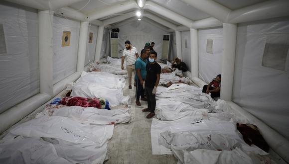 Personas junto a los cuerpos de palestinos muertos en ataques aéreos israelíes contra el hospital árabe Ahli en el centro de Gaza después de ser transportados al hospital Al-Shifa, el 17 de octubre de 2023. (Foto de Dawood NEMER / AFP)