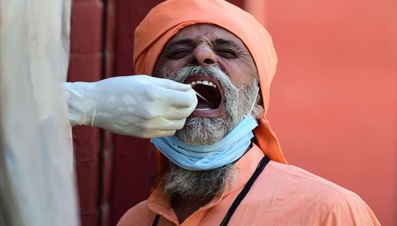 Un funcionario de salud toma una muestra de un hisopo de un hombre para realizar la prueba del coronavirus Covid-19 en un centro de pruebas en Allahabad, India, el 1 de abril de 2021. (Foto de Sanjay KANOJIA / AFP).