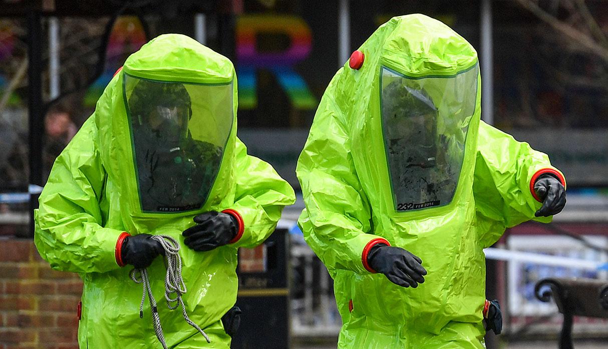 TOPSHOT - Members of the emergency services in green biohazard suits work to afix the tent over the bench where a man and a woman were found on March 4 in critical condition at The Maltings shopping centre in Salisbury, southern England, on March 8, 2018 after the tent became detached.  British detectives on March 8 scrambled to find the source of the nerve agent used in the "brazen and reckless" attempted murder of a Russian former double-agent and his daughter. Sergei Skripal, 66, who moved to Britain in a 2010 spy swap, is unconscious in a critical but stable condition in hospital along with his daughter Yulia after they collapsed on a bench outside a shopping centre on Sunday.
 / AFP / Ben STANSALL