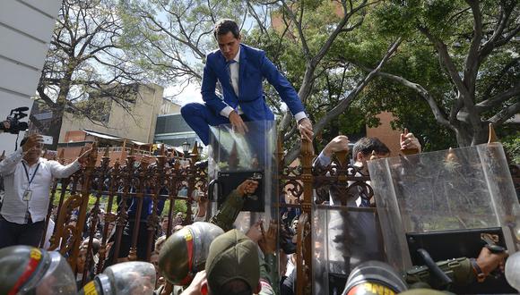 Juan Guaidó trepa una reja para intentar entrar a la Asamblea Nacional de Venezuela. (AP Photo/Matias Delacroix).