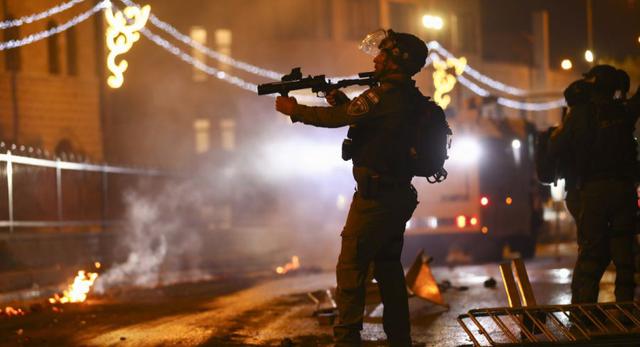 Un oficial de policía israelí apunta su rifle hacia los manifestantes palestinos durante los enfrentamientos en la Puerta de Damasco, en las afueras de la Ciudad Vieja de Jerusalén. (AP Photo / Oded Balilty).