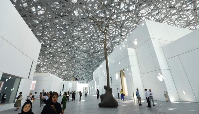 El Museo de Louvre de Abu Dhabi destaca por su majestuosa cúpula de 180 metros de diámetro y 7.500 toneladas de acero que cubre el complejo. En la imagen, las personas transitan cerca de una escultura del artista italiano Giuseppe Penone. (Foto: AFP)