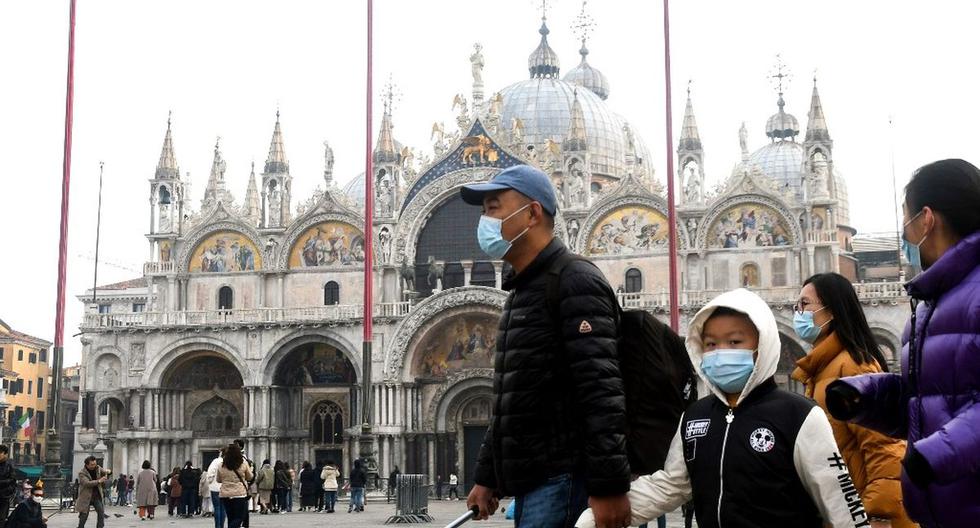 Un grupo de turistas usan máscaras protectoras mientras visitan la Piazza San Marco durante el período habitual de las festividades del Carnaval, que se han cancelado debido a un brote del COVID-19. (AFP)