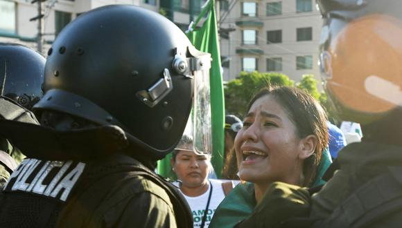 Una mujer forcejea con la policía de Bolivia durante una manifestación convocada por la Universidad Autónoma Gabriel René Moreno (UAGRM) exigiendo la liberación del gobernador de Santa Cruz, Luis Fernando Camacho. (RODRIGO URZAGASTI / AFP).