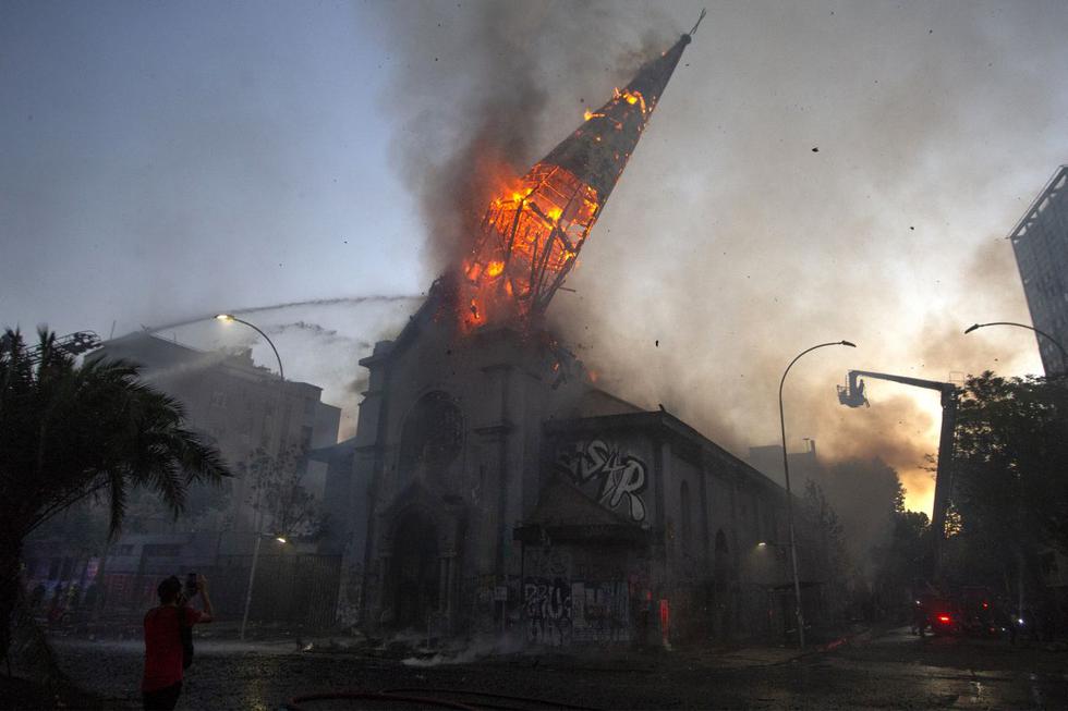 La cúpula de la iglesia de La Asunción cae ardiendo en llamas después de ser incendiada por manifestantes en la conmemoración del primer aniversario del levantamiento social en Chile. (Foto de CLAUDIO REYES / AFP).