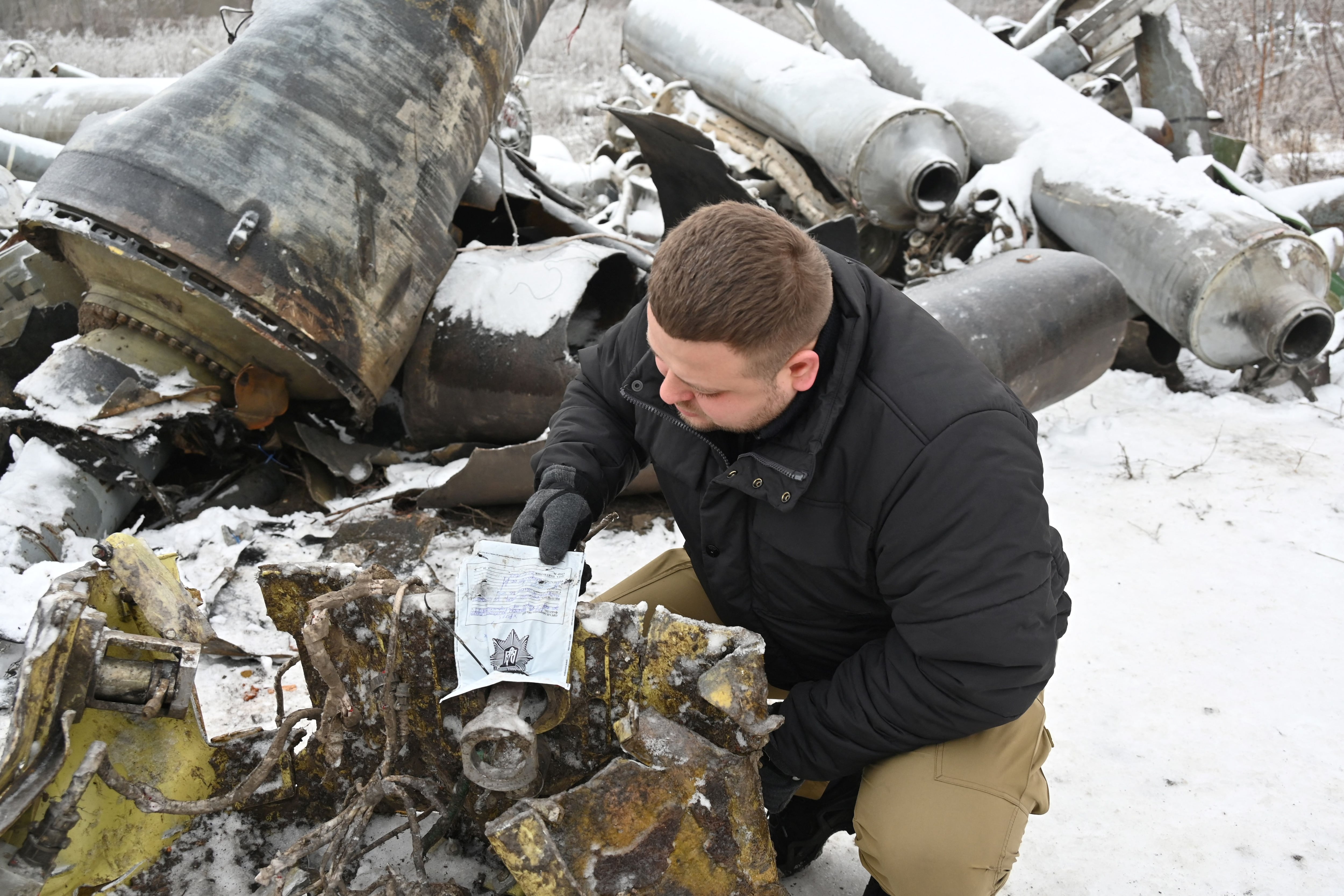 In this photo taken on January 6, 2024, a prosecutor's expert inspects the remains of a missile used during an attack on Kharkiv on January 2.  (Photo by SERGEY BOBOK/AFP).