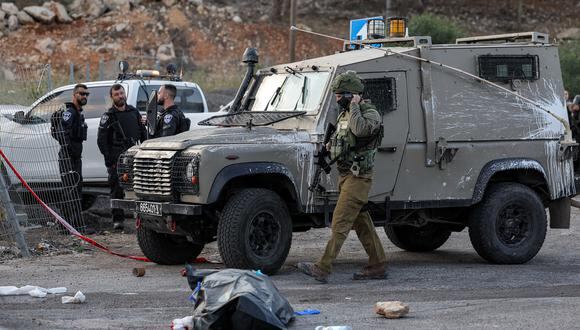 Un soldado israelí pasa junto a un cadáver en la escena de un ataque cerca del asentamiento judío de Eli en el norte de Cisjordania ocupada el 20 de junio de 2023. (Foto de AHMAD GHARABLI / AFP)