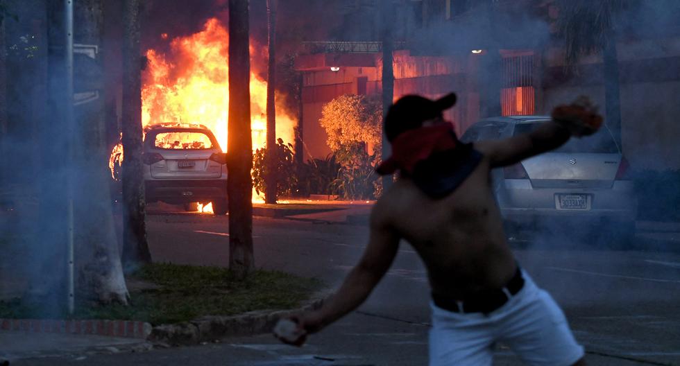 Un vehículo arde en llamas cuando un manifestante arroja una piedra a la policía antidisturbios en los alrededores del Departamento de Policía de Santa Cruz en el centro de Santa Cruz, Bolivia.