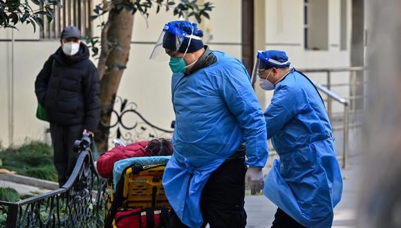 Personal con ropa protectora transporta a un paciente en una camilla junto a una clínica de fiebre de un hospital en Shanghái.