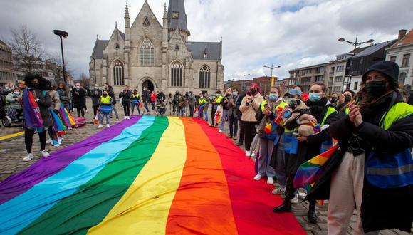 Los activistas aplauden y se paran junto a una bandera gigante del arco iris mientras asisten a la campaña "Stand up for LBGTI + Lives", en la Casa Rosa - Rainbow House East Flanders, en Beveren. (Foto: NICOLAS MAETERLINCK / AFP)
