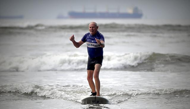 Francisco Verazani de Aguiar, de 74 años, práctica surf durante una clase que imparte "Escuela Radical", el 22 de enero de 2019, en Santos (Brasil). (EFE)