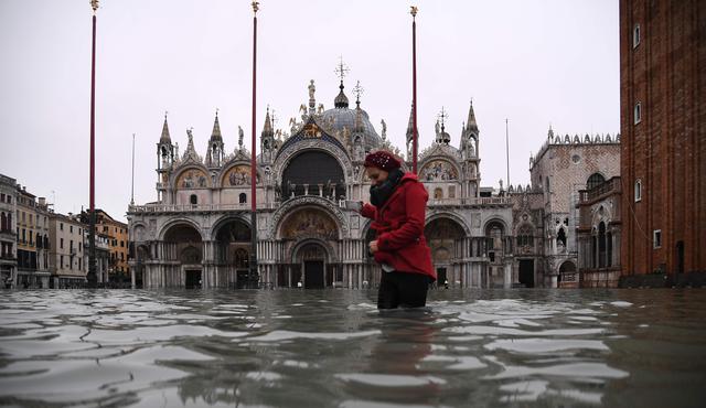 Una mujer cruza la inundada plaza de San Marcos después de un excepcional nivel de agua durante la marea alta en Venecia. (AFP / Marco Bertorello).