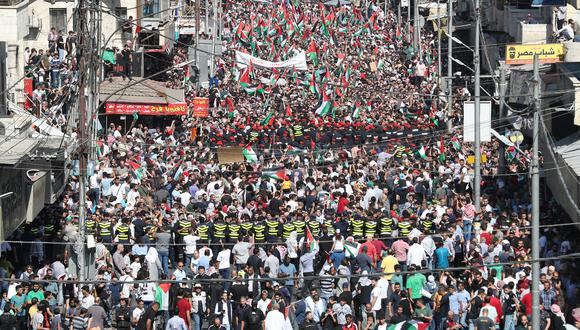 Los manifestantes ondean banderas palestinas y jordanas durante una manifestación en Ammán el 13 de octubre de 2023. (Foto de Khalil MAZRAAWI / AFP)