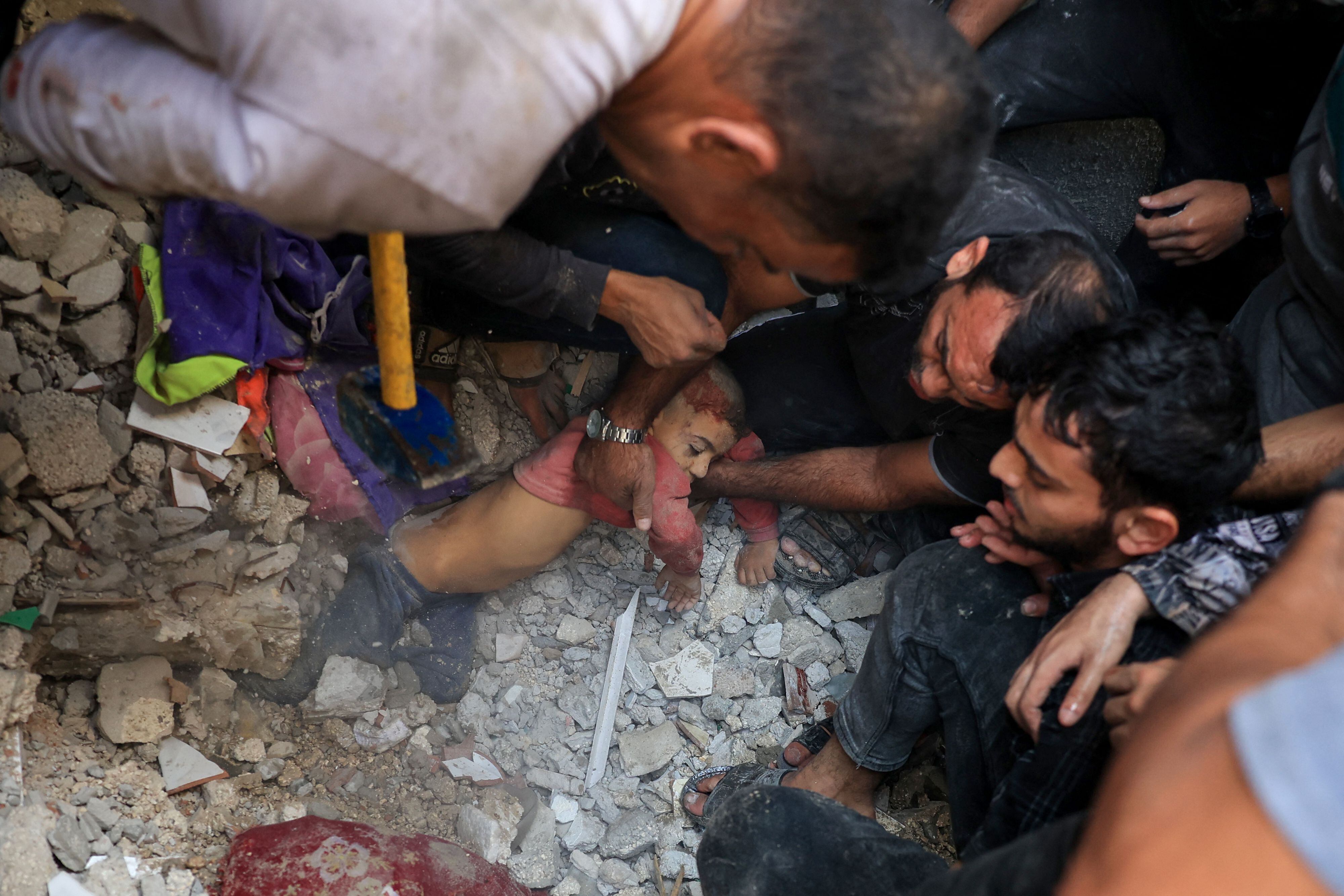Palestinians pull a child out of the rubble after an Israeli bombing in Rafah, in the south of the Gaza Strip, on November 7, 2023. (Photo by SAID KHATIB/AFP).