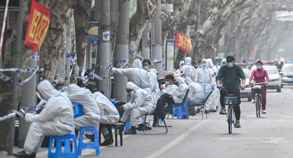 Trabajadores con ropa protectora cierran algunas áreas tras la detección de nuevos casos de coronavirus covid-19 en Shanghái, China, el 14 de marzo de 2022. (Héctor RETAMAL / AFP).
