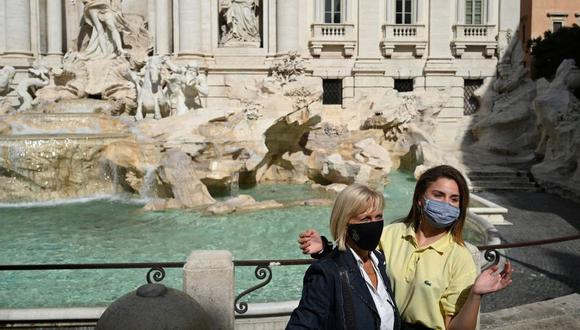 Turistas que usan mascarillas se toman fotos junto a la Fontana di Trevi en el centro de Roma el 25 de septiembre de 2020 durante la pandemia de coronavirus COVID-19. (Foto de Vincenzo PINTO / AFP).