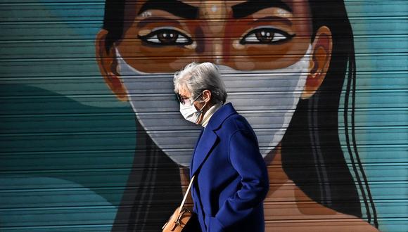 Una mujer que usa mascarilla como medida preventiva contra el coronavirus covid-19 pasa junto a un mural en Madrid, España. (GABRIEL BOUYS / AFP).