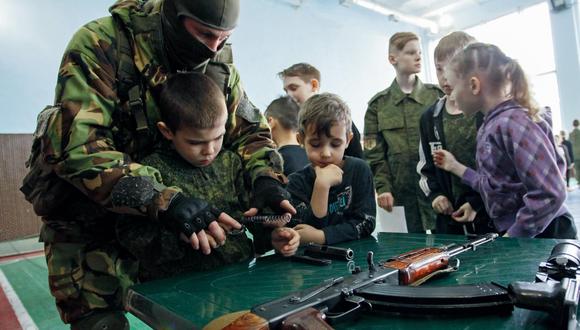 Imagen referencial tomada en el 2018. Un militar le enseña a los niños a utilizar armas en Donetsk, Ucrania. EFE