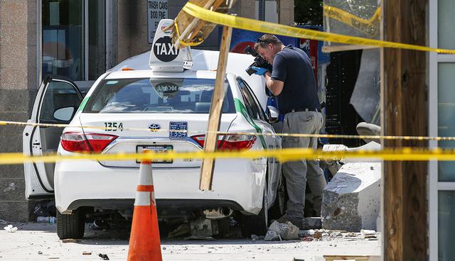 An official photographs the scene where police say a taxi driver struck a group of pedestrians, injuring several, Monday, July 3, 2017, in Boston. A police official said the crash is believed to be a case of "operator error" in which the driver stepped on the gas pedal instead of the brake. (AP Photo/Michael Dwyer)