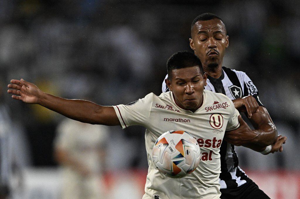 Universitario's forward Edison Flores (Front) and Botafogo's midfielder Marlon Freitas fight for the ball during the Copa Libertadores group stage first leg football match between Brazil's Botafogo and Peru's Universitario at the Nilton Santos Stadium in Rio de Janeiro, Brazil, on April 24, 2024. (Photo by MAURO PIMENTEL / AFP)