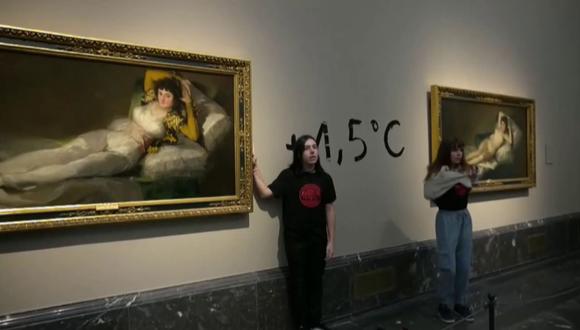 Dos activistas pegados con una mano a los marcos de dos pinturas del maestro español Francisco Goya en el museo del Prado en Madrid. (Foto de Extinction Rebellion / EFE)