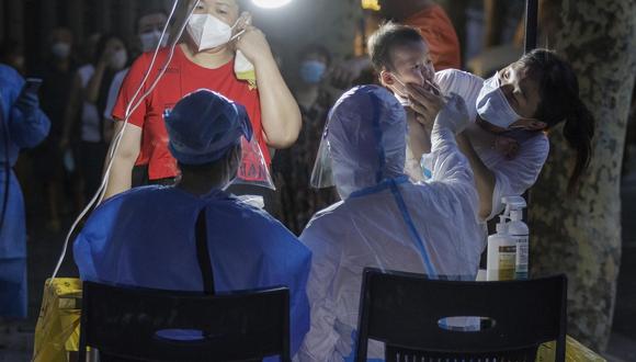 Una madre trae a un niño para la prueba PCR obligatoria de Coronavirus, en Shanghái, China.