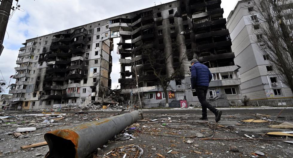Un hombre pasa frente a un fragmento de artefactos explosivos esparcidos en una calle donde se ven edificios destruidos en la ciudad de Borodianka, al noroeste de Kiev, Ucrania, el 4 de abril de 2022. (Sergei SUPINSKY / AFP).