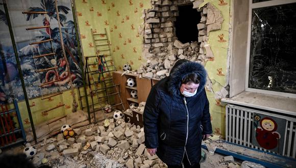 Una mujer se para entre los escombros después del bombardeo de un jardín de infantes en el asentamiento de Stanytsia Luhanska, Ucrania, el 17 de febrero de 2022. (Aris Mesinis / AFP).