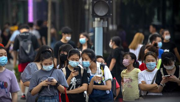 Personas que usan mascarillas para protegerse contra el coronavirus esperan para cruzar una intersección en Beijing. (Foto: AP / Mark Schiefelbein)