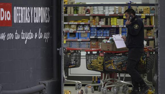 Un policía de la provincia de Buenos Aires junto a un carrito con mercancías en un supermercado "Dia" después de que fuera saqueado, en José C. Paz, en las afueras de Buenos Aires, el 22 de agosto de 2023. (Foto de Juan MABROMATA / AFP)