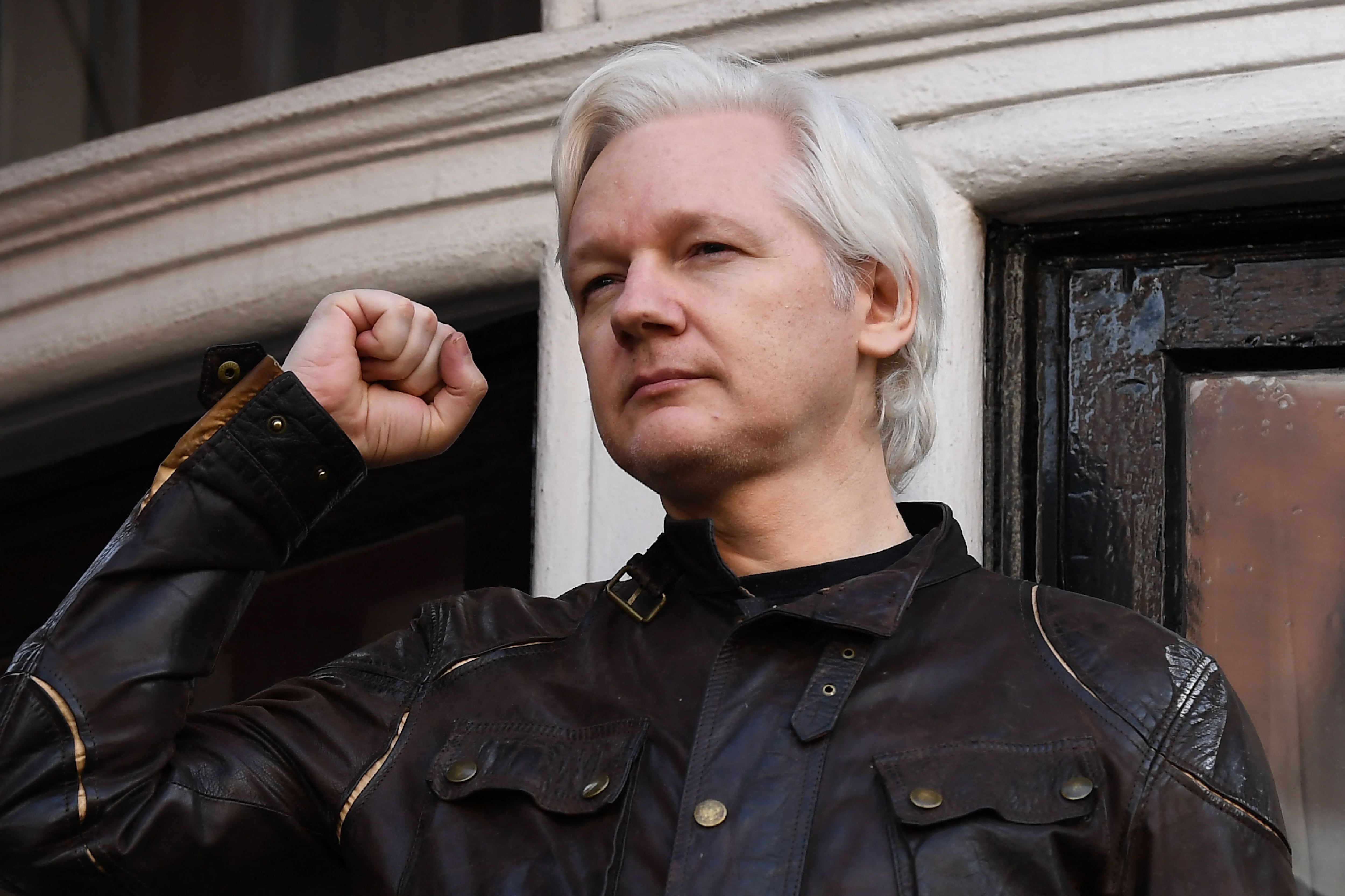 Wikileaks founder Julian Assange raises his fist before addressing the media on the balcony of the Ecuadorian Embassy in London on May 19, 2017. (Photo by Justin TALLIS/AFP).