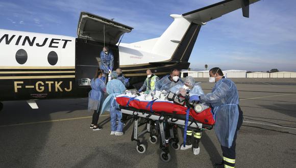 Los paramédicos transfieren a un paciente de coronavirus de una ambulancia a un avión médico en la isla mediterránea de Córcega, en Francia, el 5 de enero de 2022, antes de volar a la ciudad de Brest. (Pascal POCHARD-CASABIANCA / AFP).